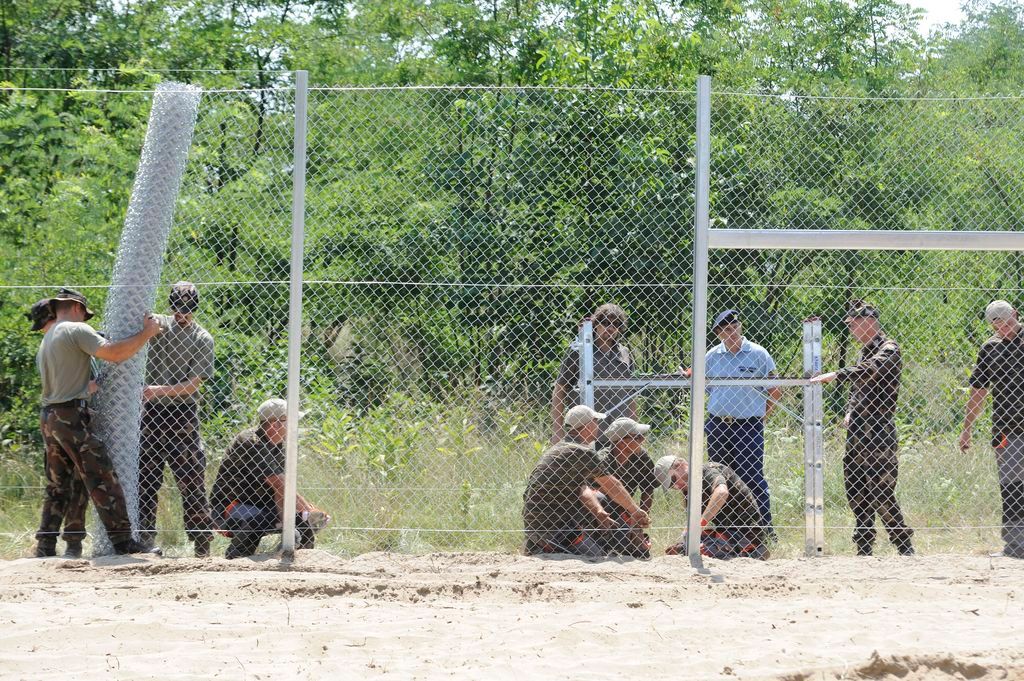 Mórahalom, 2015. július 16. Katonák és közfoglalkoztatottak dróthálót feszítenek ki a kerítésoszkopokra az ideiglenes biztonsági határzár mintaszakaszának építési munkálatai során a magyar-szerb határon, Mórahalom térségében 2015. július 16-án. MTI Fotó: Kelemen Zoltán Gergely