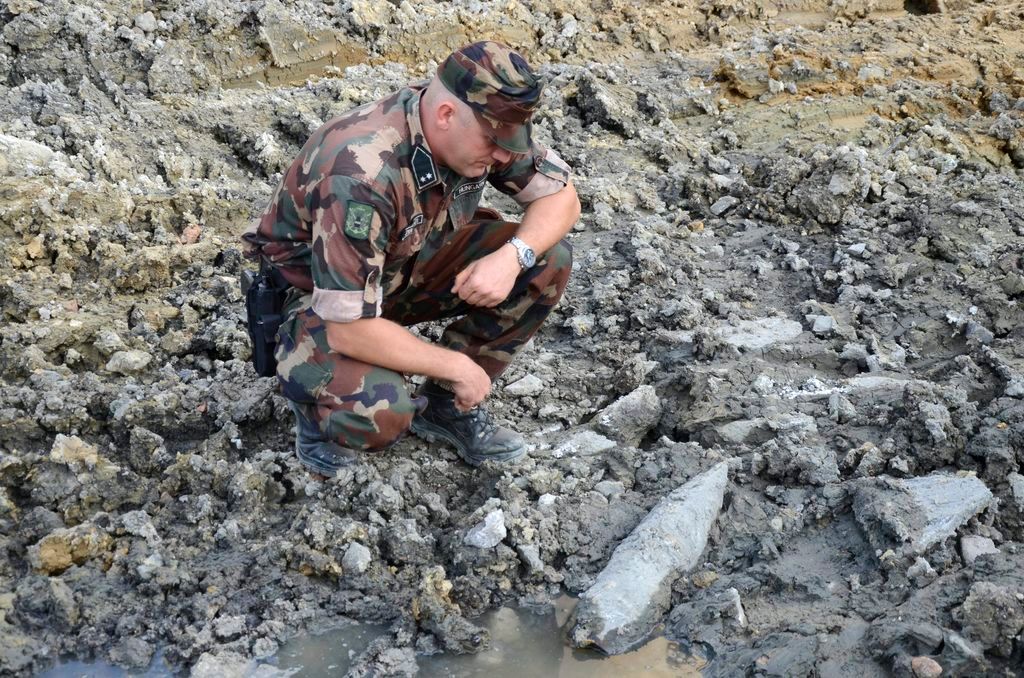 Budapest, 2015. augusztus 24. Tûzszerész guggol egy 152 milliméteres szovjet repesz-rombológránát mellett a Széll Kálmán téren 2015. augusztus 24-én. A gránát építési munkák közben, a metróbejárattól 20 méterre került elõ, a gyújtószerkezet vizsgálatának idejére 150 méter sugarú körben kiürítették és lezárták a teret. MTI Fotó: Mihádák Zoltán