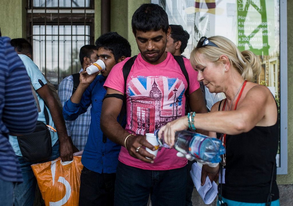 Kiskunhalas, 2015. augusztus 13. A MigSzol (Migráns Szolidaritás Csoport) Halas aktivistája vizet tölt a vasútállomásra érkezõ illegális bevándorlóknak Kiskunhalason 2015. augusztus 13-án. MTI Fotó: Ujvári Sándor