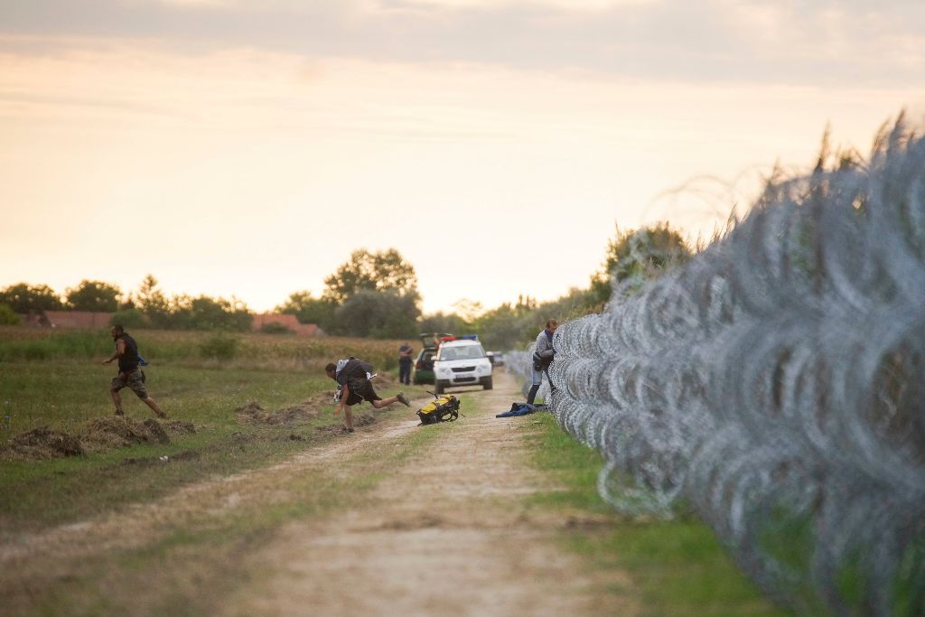 Röszke, 2015. augusztus 26. Migránsok másznak át a gyorstelepítésû drótakadályon a Röszke melletti vasúti átjáró közelében a magyar-szerb határon 2015. augusztus 26-án. MTI Fotó: Balogh Zoltán
