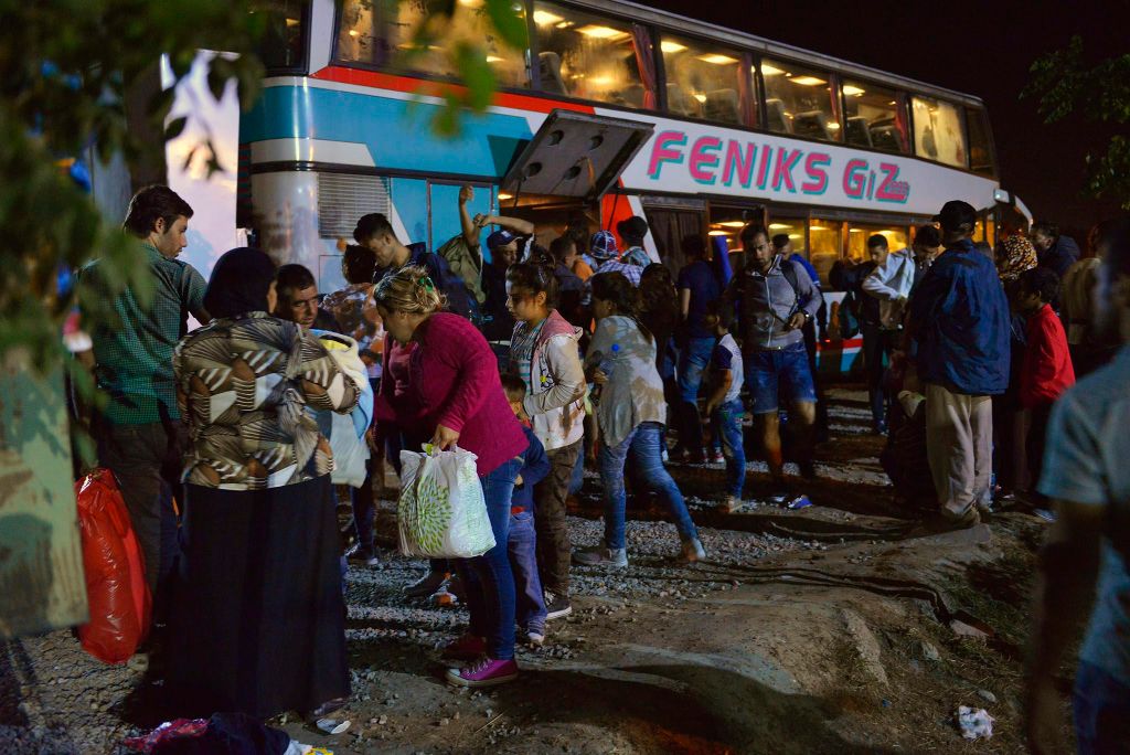 Magyarkanizsa, 2015. augusztus 26. Migránsok egy autóbusz elõtt a szerbiai Magyarkanizsa vásárterén létrehozott, 1400 ember befogadására is alkalmas ideiglenes pihenõhelynél 2015. augusztus 26-ra virradó éjjel. MTI Fotó: Molnár Edvárd