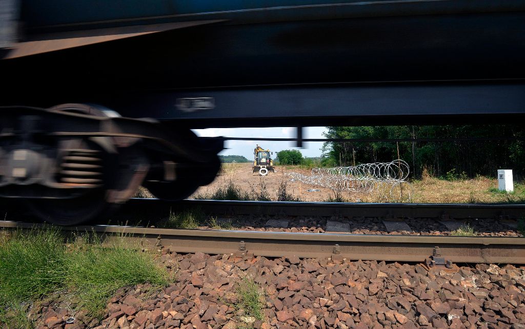 Kelebia, 2015. augusztus 5. A felszerelt szögesdrótkerítés egy szakasza az ideiglenes határzár kelebiai szakaszán, elõtérben a Budapest -Szabadka vasútvonalon közlekedõ tehervonat 2015. augusztus 5-én. MTI Fotó: Máthé Zoltán