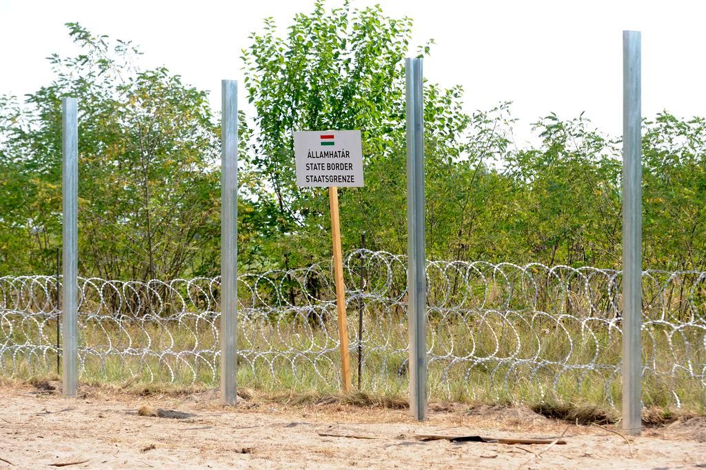 Mórahalom, 2015. augusztus 11. Az ideiglenes biztonsági határzár horganyzott acél kerítésoszlopai a gyorstelepítésû drótakadály elõtt egy háromnyelvû, a magyar államhatárra figyelmeztetõ tábla mellett Mórahalom közelében, a magyar-szerb határon 2015. augusztus 11-én. Augusztus közepére befejezõdik a gyorstelepítésû drótakadály elhelyezése a magyar-szerb határ Csongrád megyei szakaszán, Ásotthalomtól Tiszaszigetig. MTI Fotó: Kelemen Zoltán Gergely