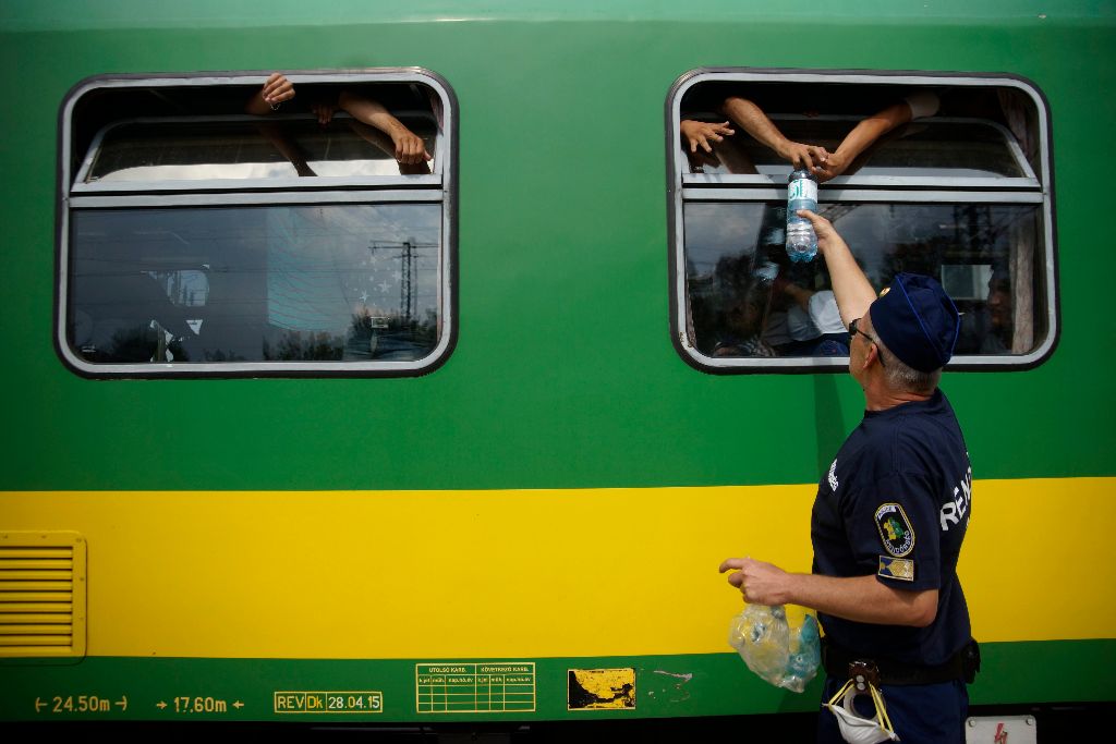 Bicske, 2015. szeptember 3. Vizet oszt egy rendõr a budapesti Keleti pályaudvarról Sopronba tartó, Bicskén megállított vonaton tartózkodó migránsoknak 2015. szeptember 3-án. MTI Fotó: Balogh Zoltán