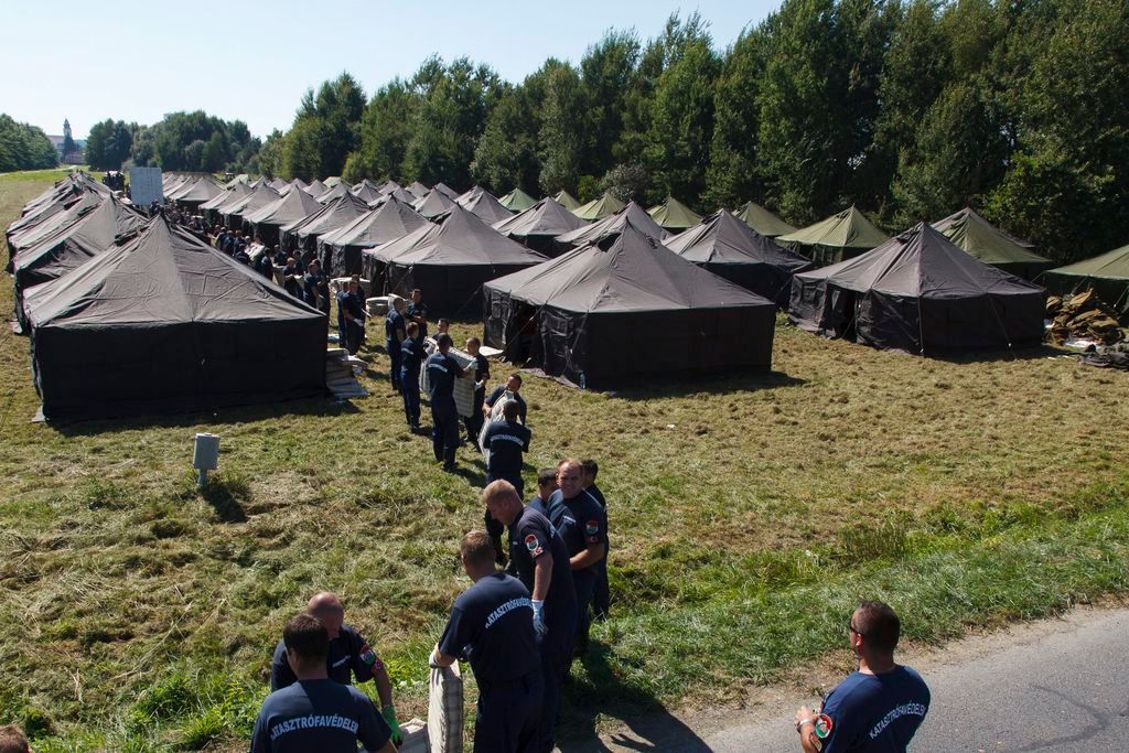 Szentgotthárd, 2015. szeptember 12. A katasztrófavédelem munkatársai ágybetéteket pakolnak a migránsok számára kialakított ideiglenes gyûjtõpont sátraihoz a szentgotthárdi ipari parkban 2015. szeptember 12-én. MTI Fotó: Varga György