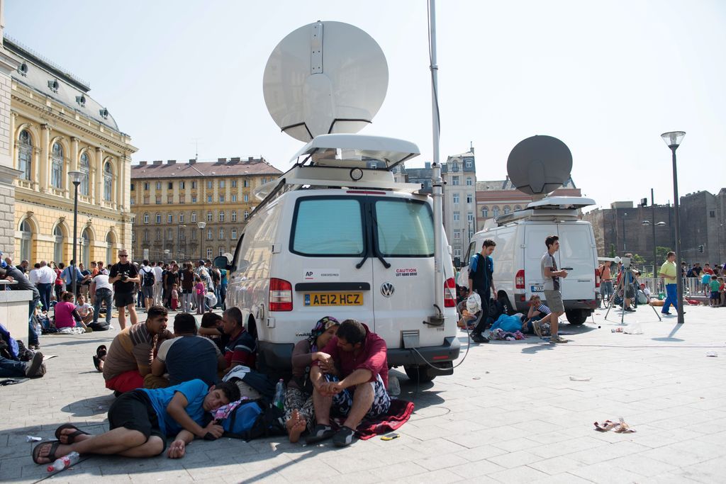Budapest, 2015. szeptember 2. Közvetítõkocsik árnyékában pihenõ illegális bevándorlók a Keleti pályaudvarnál 2015. szeptember 2-án. MTI Fotó: Kallos Bea