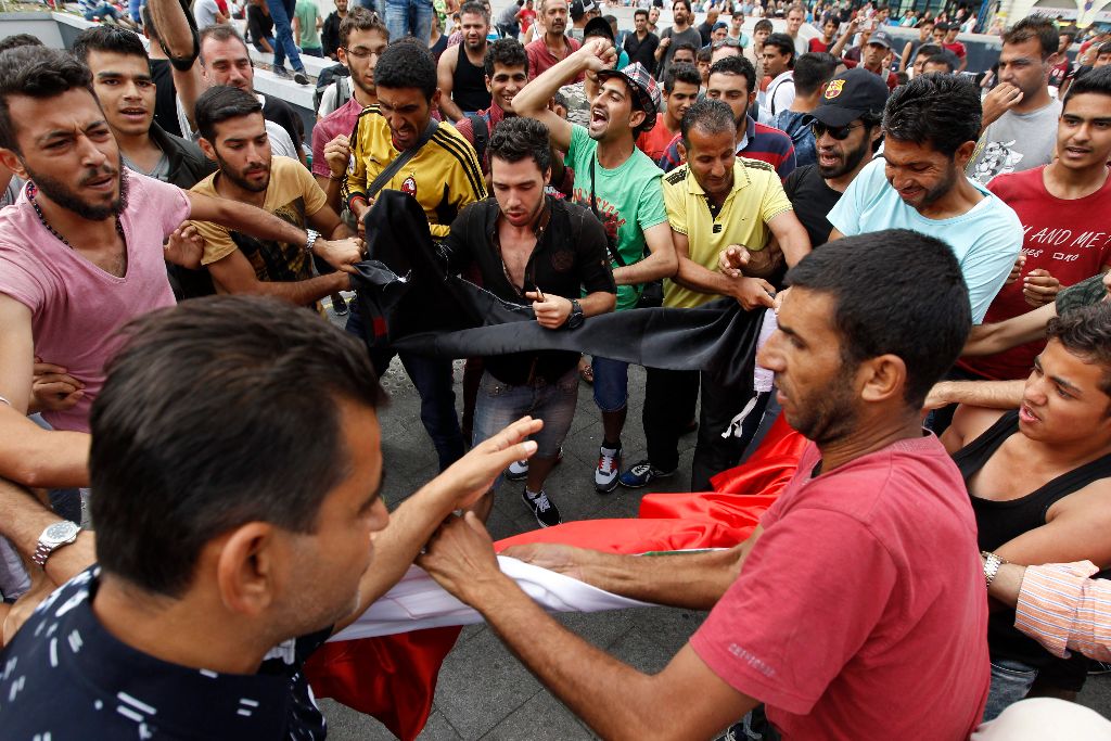 Budapest, 2015. szeptember 3. Migránsok tépnek szét egy szír kormánypárti zászlót, miközben a Keleti pályaudvar elõtt demonstrálnak 2015. szeptember 3-án. MTI Fotó: Szigetváry Zsolt