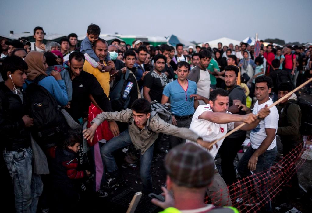 Röszke, 2015. szeptember 12. Egy dulakodó migráns kezébõl botot csavar ki egy önkénes segítõ, miközben buszra várnak a röszkei Dugonyi úti rendõrségi gyûjtõponton 2015. szeptember 13-án. MTI Fotó: Mohai Balázs