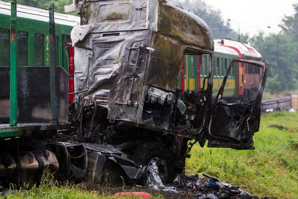 Barcs, 2016. július 25. Összeroncsolódott, kiégett kamion egy személyvonat mellett egy barcsi vasúti átjárónál 2016. július 25-én, miután a két jármû összeütközött. A kamion az ütközés következtében kigyulladt, vezetõje a helyszínen meghalt. A Sopron és Pécs között közlekedõ szerelvény mozdonyvezetõje és egy utasa könnyû sérülést szenvedett. MTI Fotó: Varga György