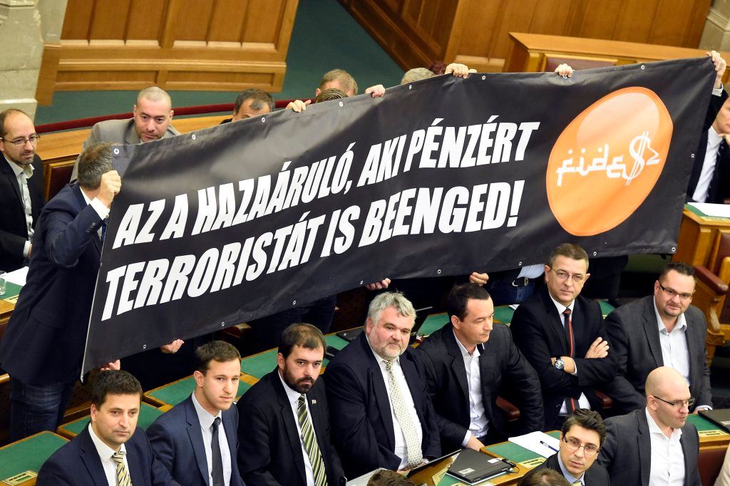 Budapest, 2016. november 8. Jobbikos képviselõk Az a hazaáruló, aki pénzért terroristát is beenged! feliratú molinót tartanak az alaptörvény hetedik módosításáról szóló szavazás alatt az Országgyûlés plenáris ülésén 2016. november 8-án. 131 képviselõ szavazott igennel, 3 nemmel, így nem kapta meg a kétharmados támogatást Orbán Viktor miniszterelnök alkotmánymódosítási javaslata, amely kimondta volna, hogy Magyarországra idegen népesség nem telepíthetõ be. MTI Fotó: Kovács Tamás